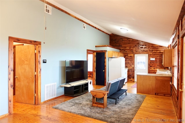 living room with wooden walls, high vaulted ceiling, and light hardwood / wood-style floors