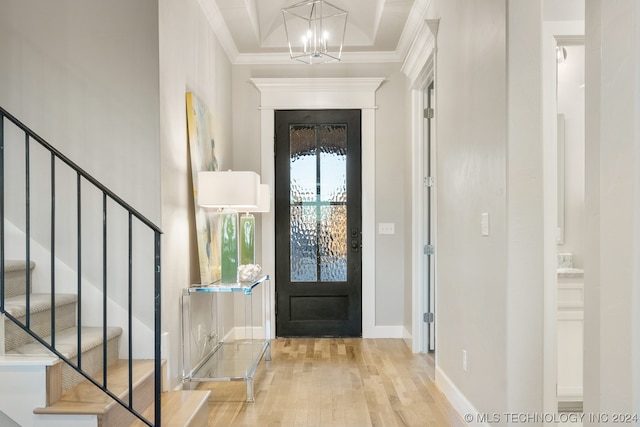 foyer entrance featuring crown molding, light hardwood / wood-style floors, and a chandelier