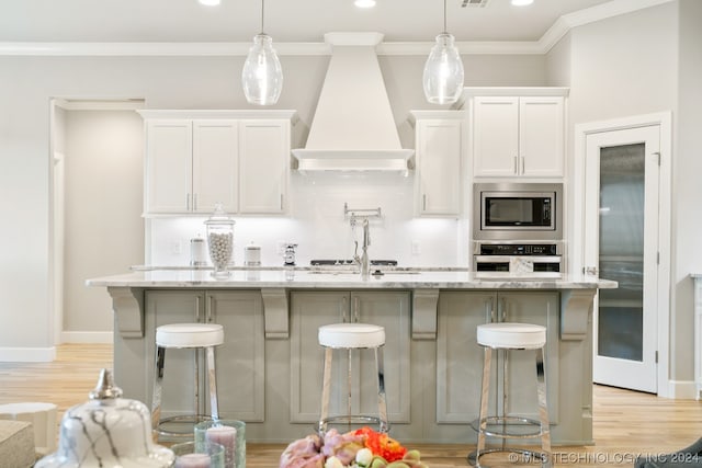 kitchen featuring a kitchen breakfast bar, stainless steel appliances, pendant lighting, and custom exhaust hood