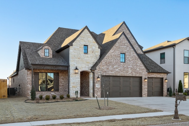 french country home featuring central AC and a garage