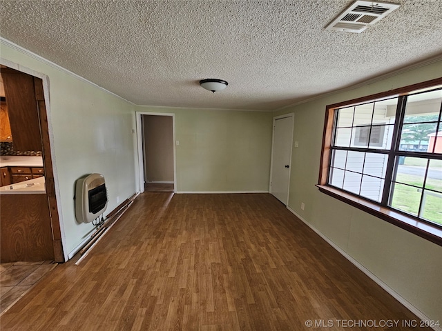 unfurnished living room with dark hardwood / wood-style floors, crown molding, a textured ceiling, and heating unit