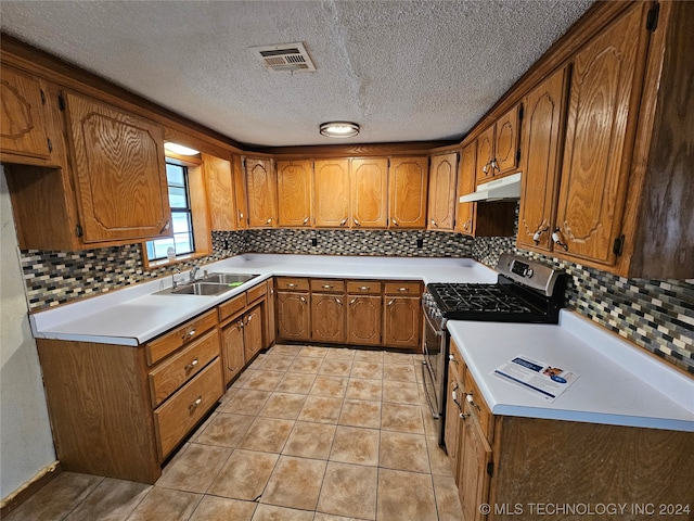 kitchen featuring tasteful backsplash, stainless steel range with gas cooktop, sink, and a textured ceiling