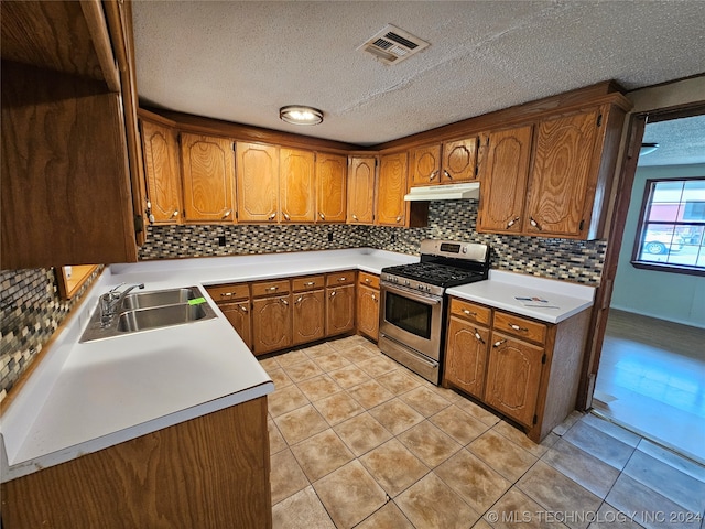 kitchen with light tile patterned flooring, sink, a textured ceiling, and gas range