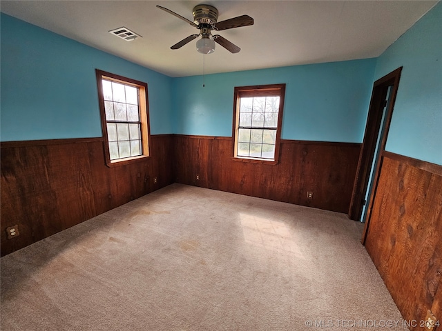 carpeted spare room featuring ceiling fan and plenty of natural light