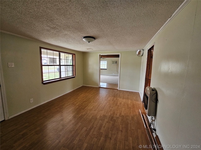 spare room with a textured ceiling, crown molding, dark wood-type flooring, and heating unit