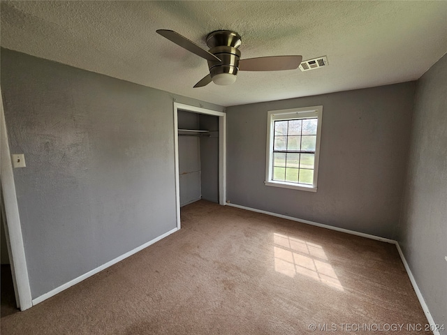 unfurnished bedroom with carpet, a textured ceiling, a closet, and ceiling fan