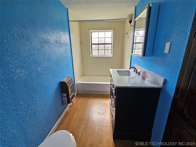 bathroom with hardwood / wood-style floors, vanity, toilet, a textured ceiling, and heating unit