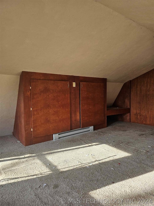 additional living space with a baseboard heating unit, carpet flooring, and vaulted ceiling