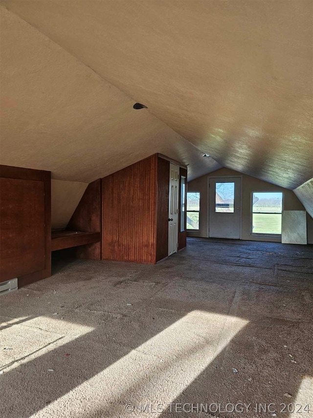 bonus room with lofted ceiling and dark colored carpet