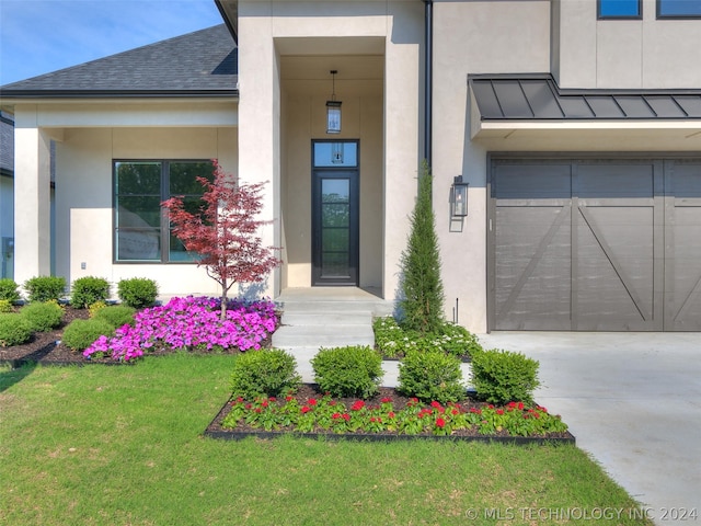 entrance to property with a garage and a lawn