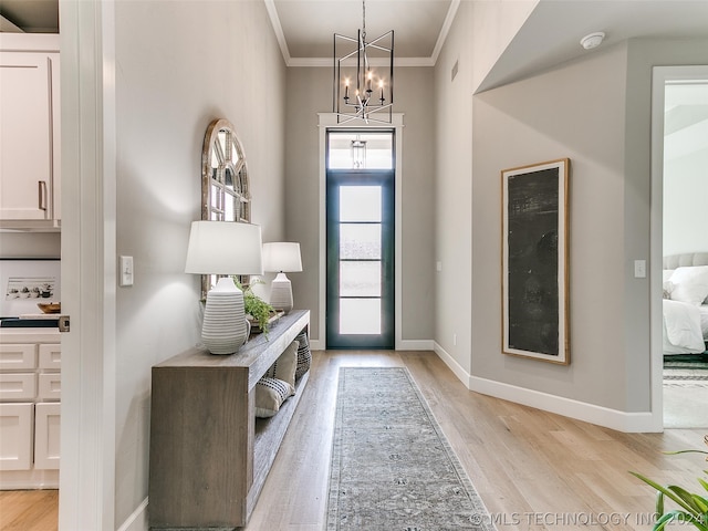 entryway featuring light hardwood / wood-style floors, ornamental molding, and a notable chandelier