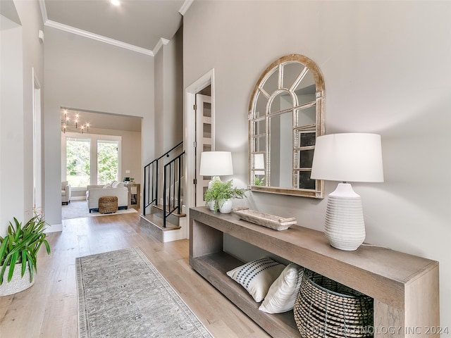 entryway with light hardwood / wood-style flooring, crown molding, and an inviting chandelier