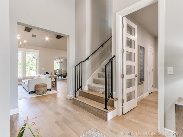 stairs with a chandelier and light wood-type flooring