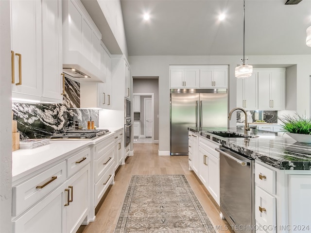 kitchen featuring wall chimney exhaust hood, light hardwood / wood-style flooring, white cabinets, and backsplash