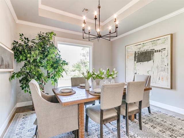 dining area with a chandelier, hardwood / wood-style flooring, a raised ceiling, and crown molding