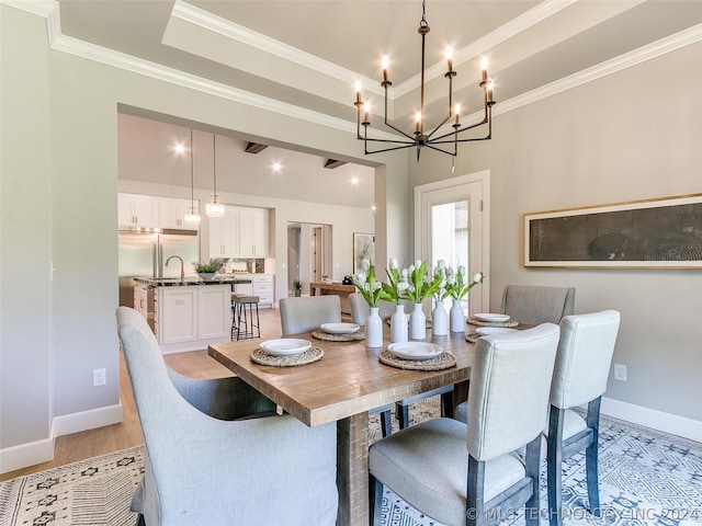 dining space featuring a tray ceiling, ornamental molding, light hardwood / wood-style floors, and a notable chandelier