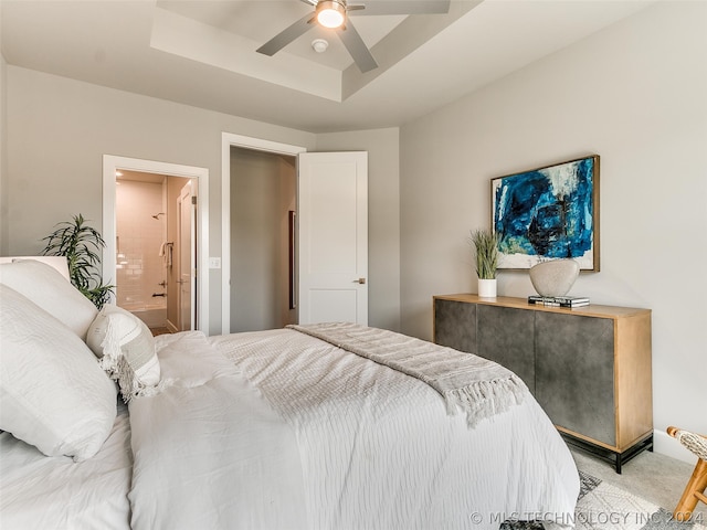 carpeted bedroom featuring ensuite bathroom, ceiling fan, and a raised ceiling