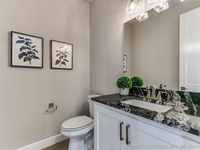 bathroom featuring hardwood / wood-style flooring, toilet, and vanity with extensive cabinet space