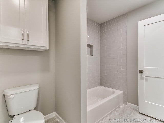 bathroom with tile flooring, toilet, and tiled shower / bath combo