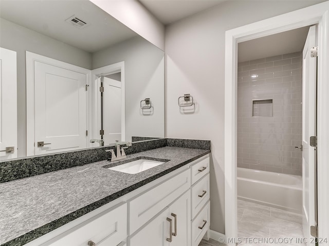 bathroom featuring tiled shower / bath, vanity, and tile floors