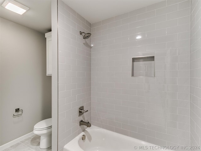 bathroom with tile flooring, toilet, and tiled shower / bath combo