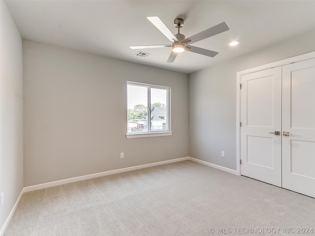 unfurnished bedroom with ceiling fan, a closet, and light colored carpet