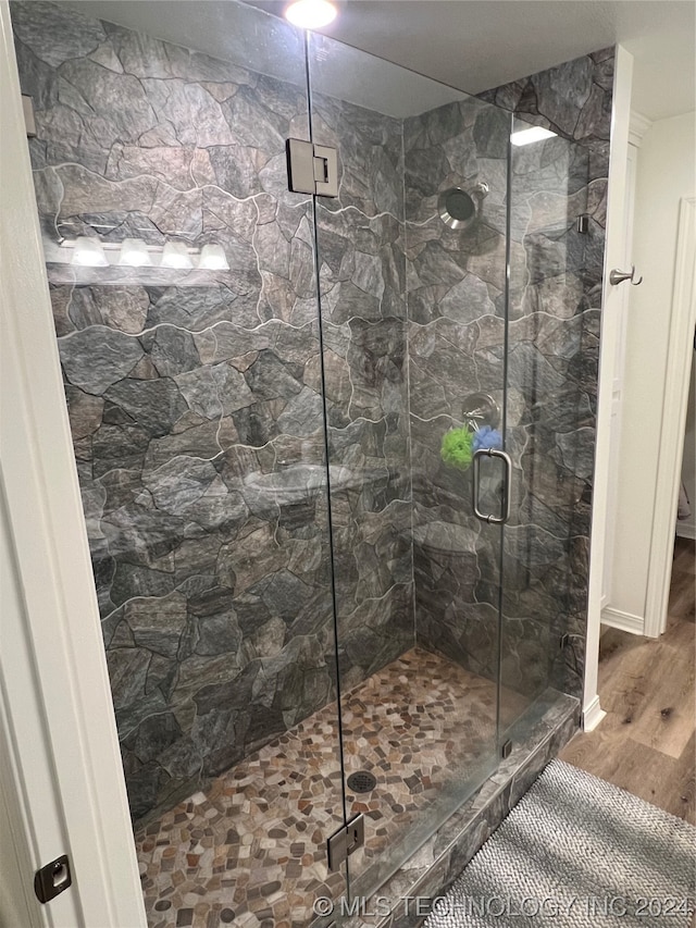 bathroom with hardwood / wood-style floors and an enclosed shower