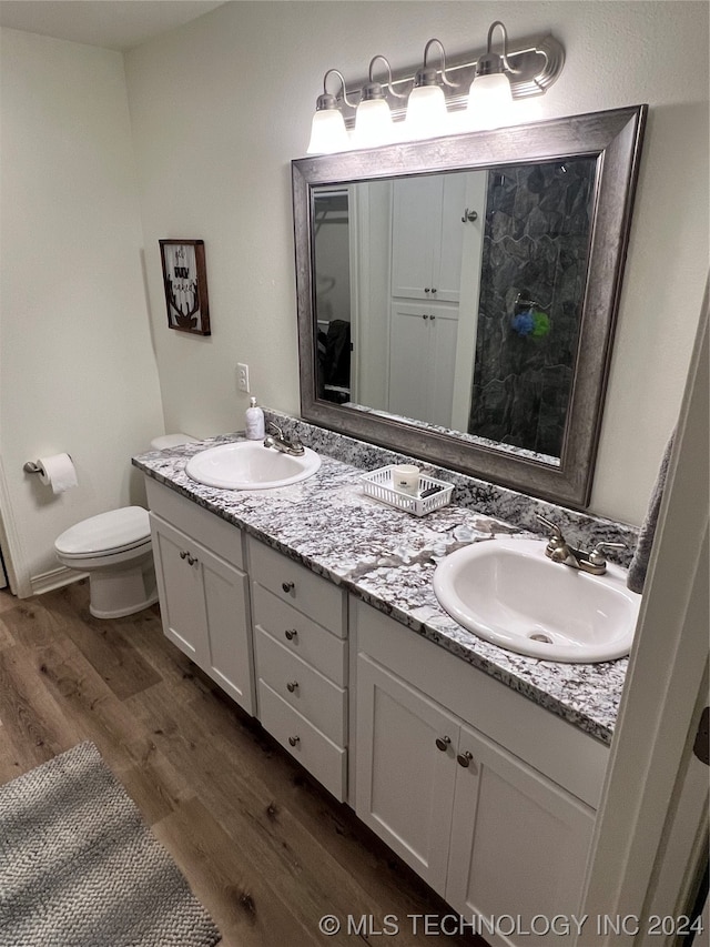 bathroom featuring double sink, hardwood / wood-style floors, large vanity, and toilet