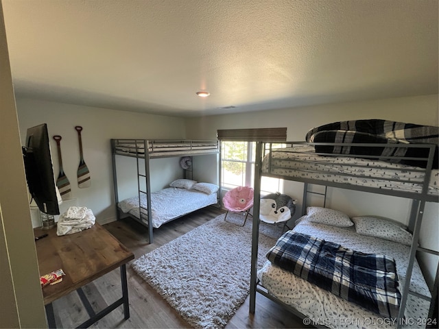 bedroom with dark hardwood / wood-style floors and a textured ceiling