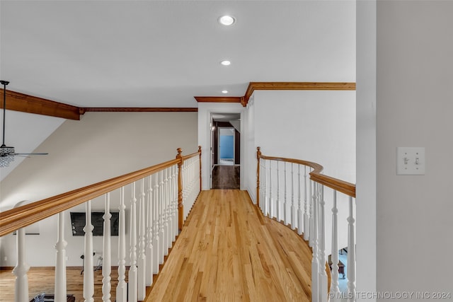 hallway featuring light hardwood / wood-style floors, ornamental molding, and vaulted ceiling with beams