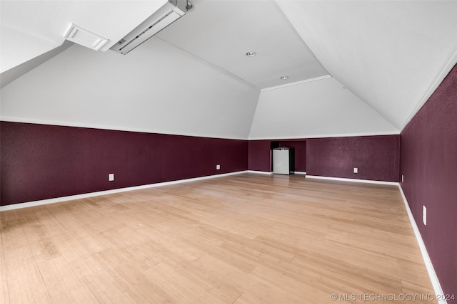 bonus room featuring light hardwood / wood-style floors, vaulted ceiling, and a wall mounted AC