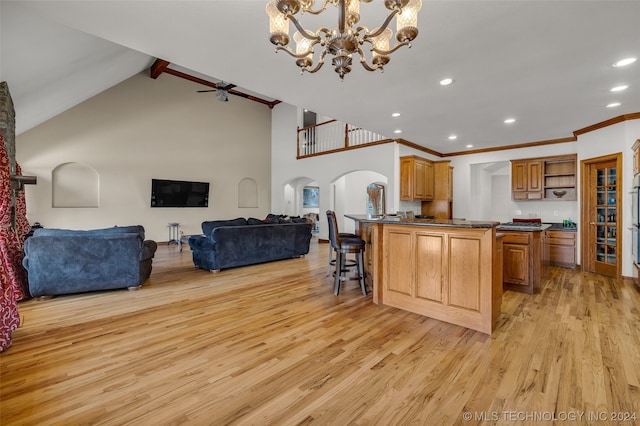 kitchen featuring a breakfast bar area, light wood-type flooring, pendant lighting, high vaulted ceiling, and ceiling fan with notable chandelier