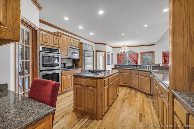 kitchen with a notable chandelier, light hardwood / wood-style flooring, a center island, and appliances with stainless steel finishes