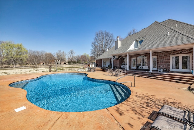 view of swimming pool with french doors and a patio