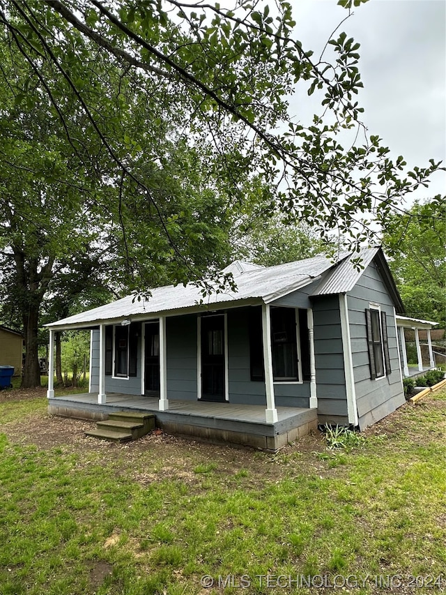 rear view of property featuring a porch and a yard