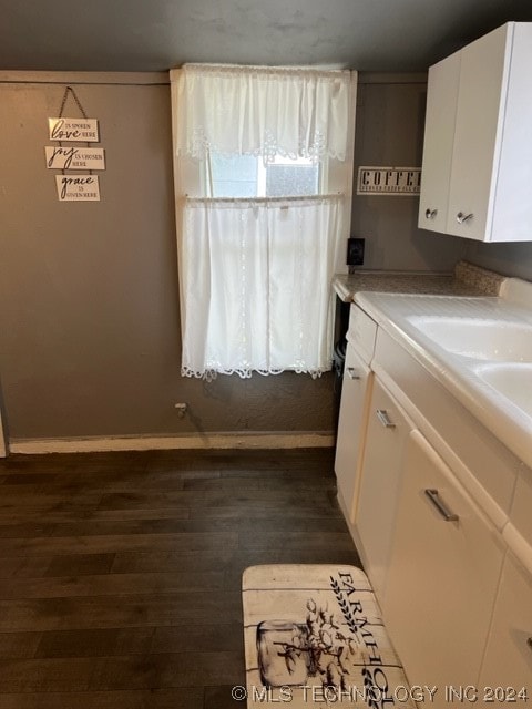 kitchen with dark wood-type flooring and white cabinetry