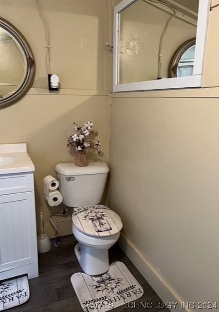 bathroom with toilet, vanity, and wood-type flooring