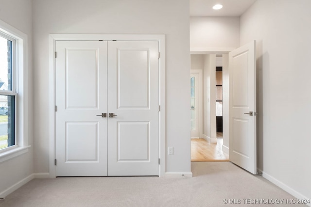 unfurnished bedroom with a closet, light carpet, and multiple windows