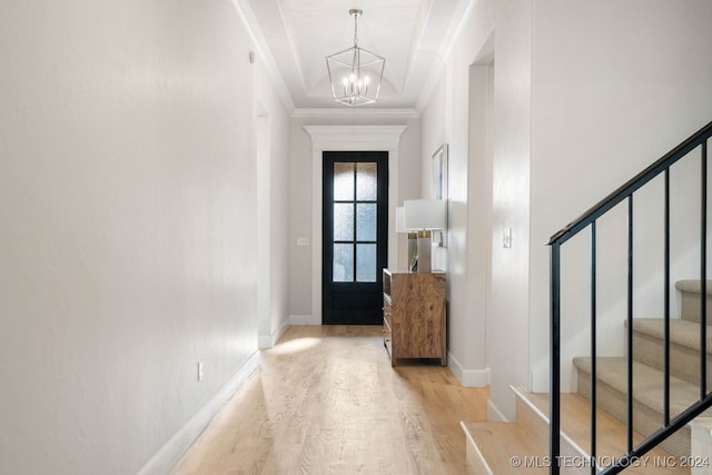 entrance foyer with crown molding, an inviting chandelier, and light hardwood / wood-style floors