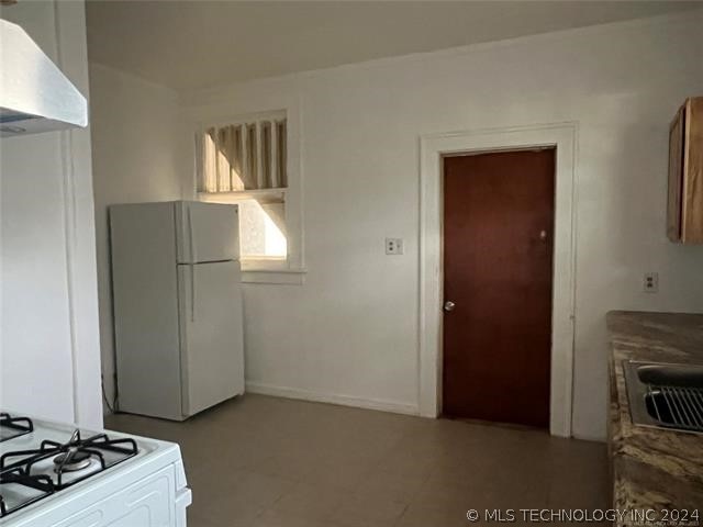 kitchen with white refrigerator, premium range hood, and light tile floors