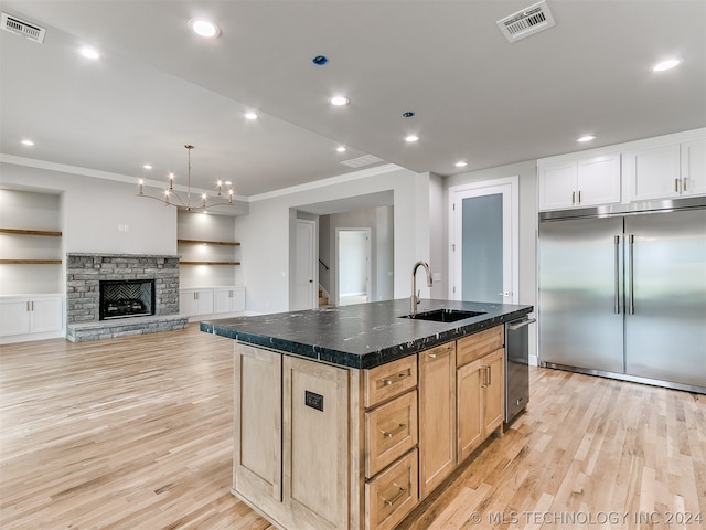 kitchen featuring sink, appliances with stainless steel finishes, light hardwood / wood-style floors, and a center island with sink