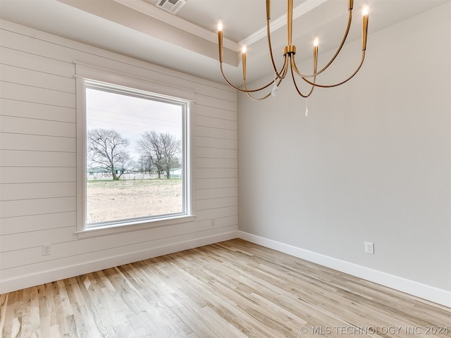 spare room with an inviting chandelier and light hardwood / wood-style flooring