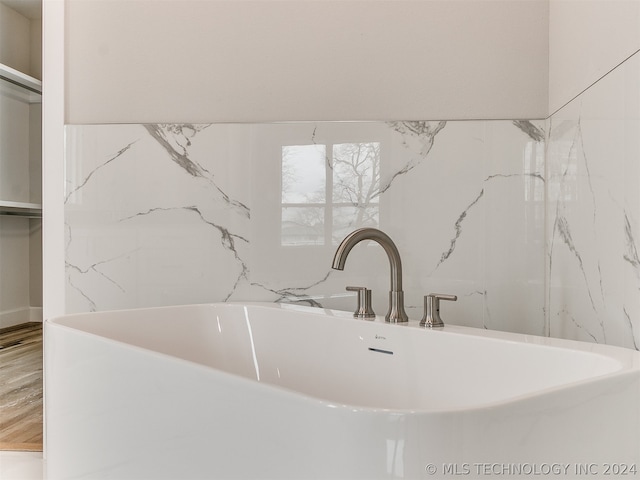 interior space featuring hardwood / wood-style flooring, a bathtub, and sink