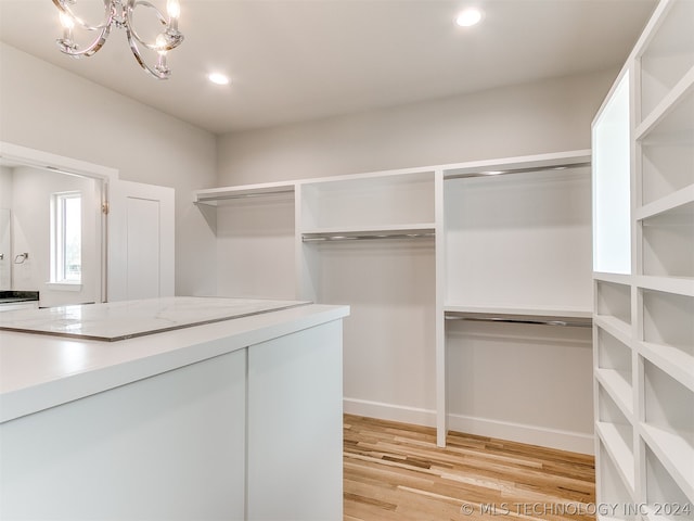 walk in closet with light hardwood / wood-style floors and a chandelier