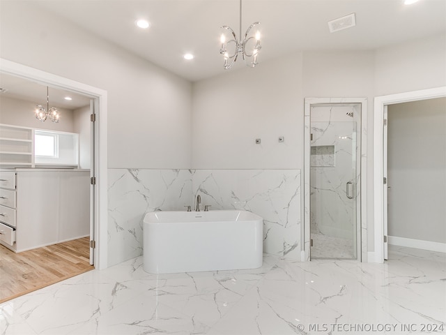 bathroom featuring tile flooring, tile walls, separate shower and tub, and an inviting chandelier