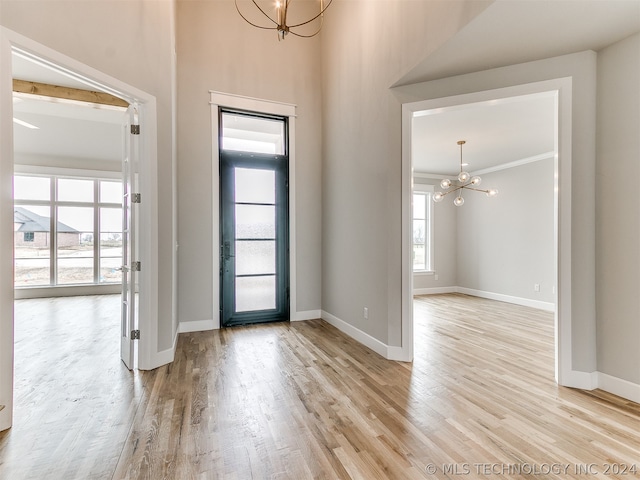 entrance foyer featuring an inviting chandelier, light hardwood / wood-style flooring, and a high ceiling