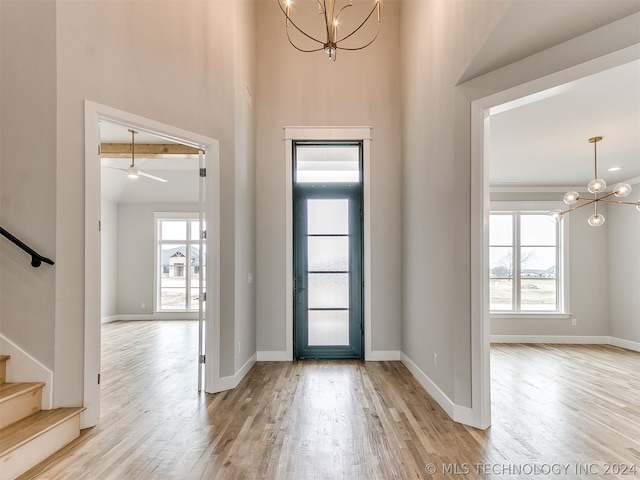 entryway with a healthy amount of sunlight, light hardwood / wood-style flooring, and a towering ceiling