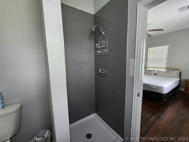 bathroom featuring hardwood / wood-style floors, ceiling fan, toilet, and a tile shower