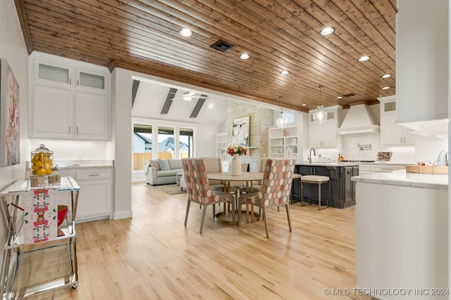 dining area with light wood-type flooring, wooden ceiling, sink, and vaulted ceiling with beams