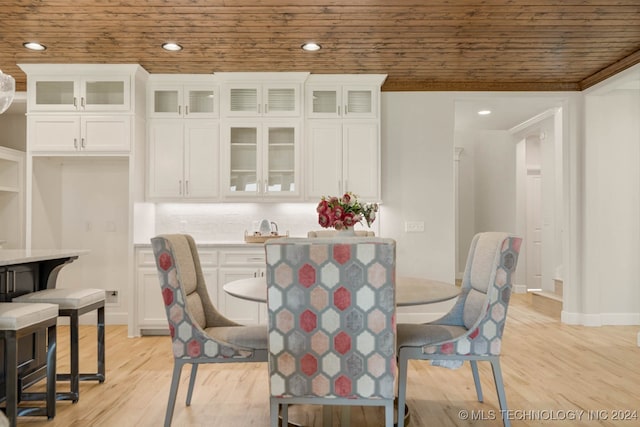 dining space featuring light hardwood / wood-style flooring, crown molding, and wooden ceiling